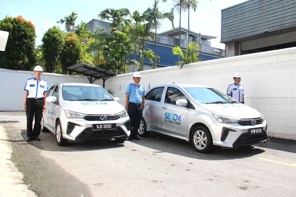 SECOM security personnel standing beside patrol vehicles for mobile response and security monitoring services