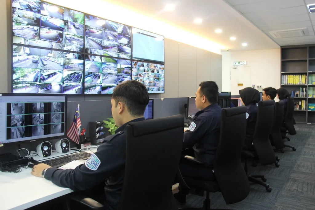 Security guard monitoring a central monitoring system video wall with live CCTV surveillance feeds