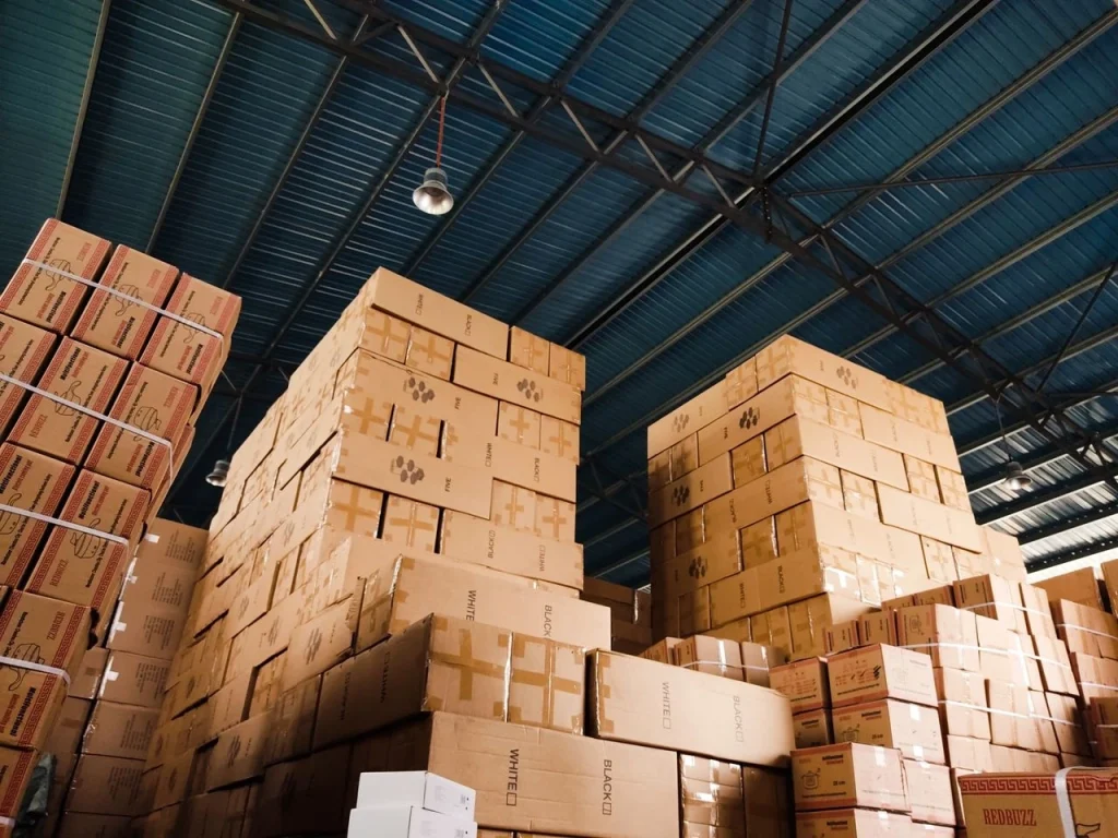 Stacked cardboard boxes under the warehouse roof: "Stacked inventory boxes in a warehouse storage area secured under warehouse security best practices"
